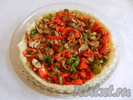 Достать форму со слоёным тестом из духовки. Выложить на тесто грибную начинку.