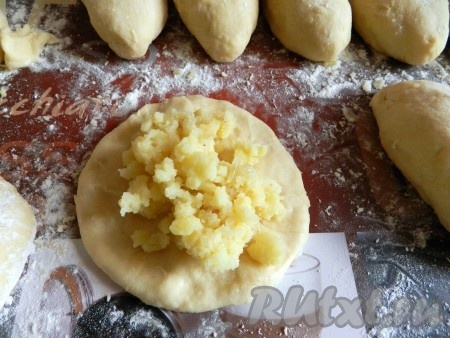 Каждый шарик из теста на присыпанной мукой поверхности размять руками в лепёшку (можно раскатывать скалкой), на середину выкладывать примерно столовую ложку картофельной начинки и, поднимая края теста над начинкой, формовать пирожок.