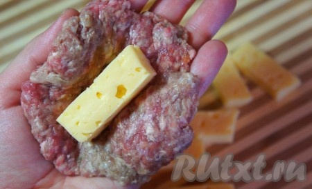 Фаршу дать немного "отдохнуть". Тем временем, приготовим начинку. Для этого сыр нарезать брусками. Влажными руками сформировать "лепёшку" из фарша, положить кусочек сыра. Далее сформировать котлету.
