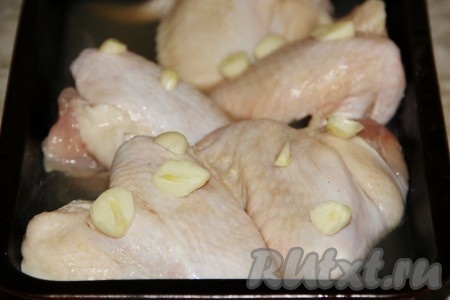 Порезанную на части курицу моем, обсушиваем и выкладываем на противень. Заливаем сверху карамельной жидкостью, которую мы приготовили ранее. Чеснок нарезаем и выкладываем на курочку.
