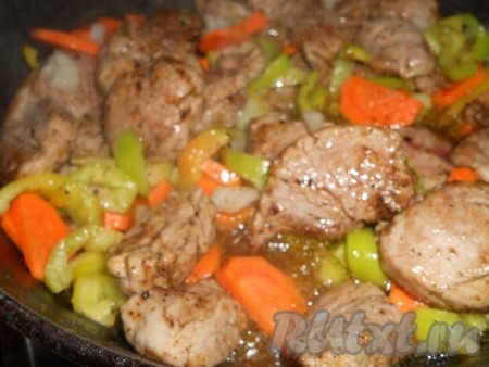 На сковороду налить растительное масло, разогреть его, выложить морковь, нарезанную на тонкие полукружочки, и мелко нарезанный лук, перемешать овощи и обжаривать в течение 5-7 минут на среднем огне, иногда помешивая. Затем добавить болгарский перец, нарезанный на полоски, перемешать, обжаривать 2-3 минуты, иногда помешивая. К обжаренным овощам выложить кусочки свинины. Обжаривать мясо с овощами минут 7-10, периодически помешивая.