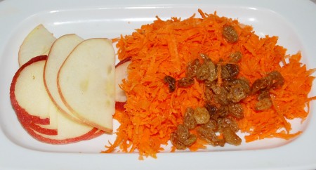 Ломтики яблока и изюм добавить к натертой моркови.