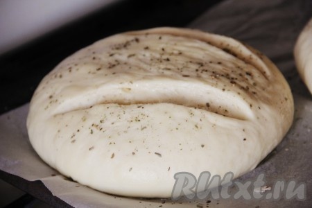 Когда тесто увеличится в размерах, можно браться за его дальнейшее приготовление. Я разделила его на 2 части, каждую часть вымесила и сформировала из нее будущий венгерский хлеб. Сделала надрезы с помощью лезвия, смазала растопленным сливочным маслом и присыпала орегано (это по вашему желанию, можно использовать любую пряность или приправу). Оставить на расстойку примерно на 1 час.
