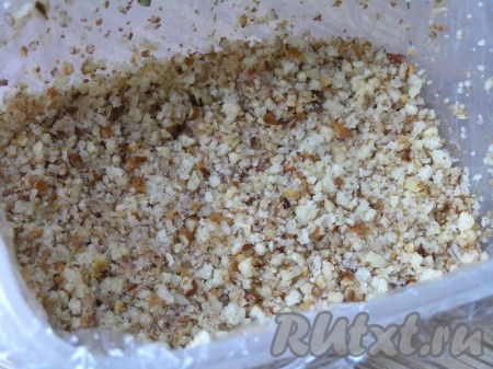 Прямоугольную форму застелить пищевой пленкой, смазать маслом, выложить измельченную ореховую смесь, разровнять, немного придавливая.