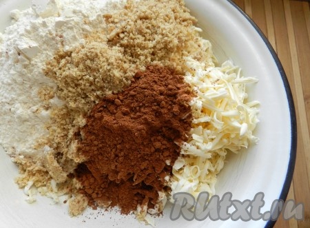 Сливочное масло достать из холодильника, натереть на крупной тёрке в глубокую миску, добавить 200 грамм муки, измельчённые орехи, ванильный сахар и 2 столовых ложки с горкой какао.