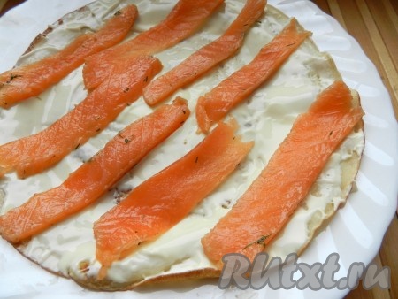 Солёную красную рыбу (у меня - лосось) нарезать на тонкие полоски, разложить поверх сыра. Можно сверху ещё посыпать мелко нарезанной свежей зеленью.