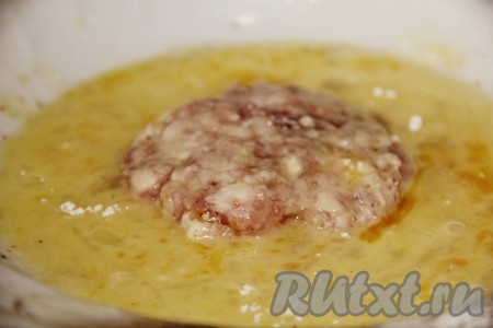 Приготовить кляр, для этого в глубокую тарелку вбить сырые яйца и взболтать их вилкой до однородности вместе с выдавленным через пресс чесноком, солью и чёрным молотым перцем. Каждый порционный кусочек фарша руками распластать в лепёшку. Обсыпать лепёшку мукой с двух сторон, а затем обмакнуть в яичный кляр с двух сторон.