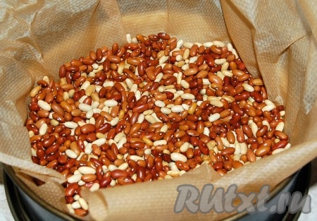 Затем форму с тестом выстелить бумагой для выпечки и насыпать в нее фасоль или рис в качестве груза. Отправить выпекаться в заранее нагретую до 180 градусов духовку на 30 минут.