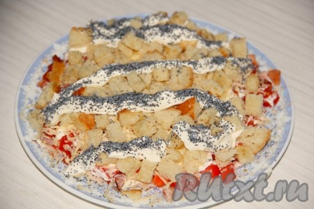 Выкладываем сухарики на слой сыра. Сверху выдавливаем змейкой майонез, который присыпаем маком.