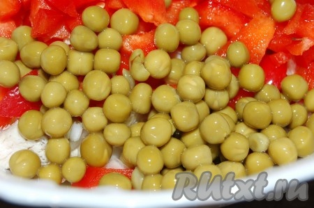 Консервированный зеленый горошек отцедить от лишней жидкости и добавить в миску с салатом.