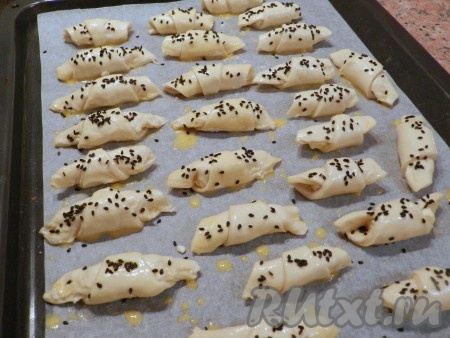 Яйцо размешать и смазать кисточкой поверхность рогаликов. Сверху посыпать черным кунжутом.