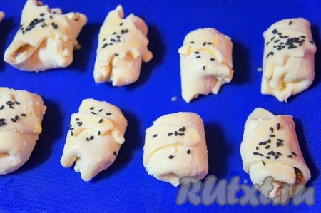 Выкладываем творожные рогалики на противень (я использовала силиконовый коврик, можно воспользоваться бумагой для выпечки, предварительно немного смазав её растительным маслом). Смазываем рогалики взбитым яйцом и посыпаем кунжутом.
