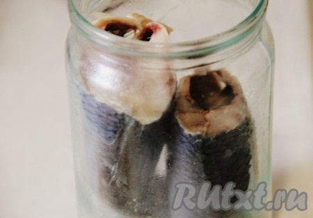 У селёдки удалить голову, выпотрошить, убирая внутренности и чёрную плёнку внутри брюшка, отрезать плавники. Подготовленную селёдку плотно выложить в подходящую по объёму стеклянную банку.