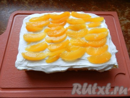 На одну половину бисквита выложить часть творожного крема. Абрикосы нарезать небольшими дольками и разложить поверх крема, сверху разложить еще один слой крема. Накрыть второй половиной бисквита. 