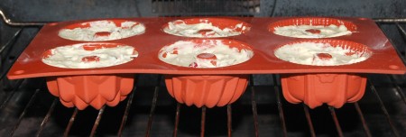 Ягоды добавить в тесто. Аккуратно подмешать ягоды и переложить тесто в силиконовые формочки, заполняя их на 2/3 объёма. Отправить кексы в заранее нагретую до 170 градусов духовку на 35 минут.