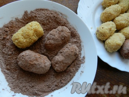 В отдельную тарелку просеять какао и сахарную пудру и обвалять в этой смеси каждое пирожное. Дать пирожным "Картошка" полежать и снова обвалять в смеси какао и сахарной пудры. Каждое пирожное украсить половинкой арахиса.