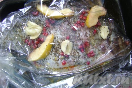Положила фаршированного леща в рукав для запекания. На рыбу выложила кусочки айвы, чеснок и еще посыпала зернами граната, чуть раздавив их, тем самым полив соком леща.
