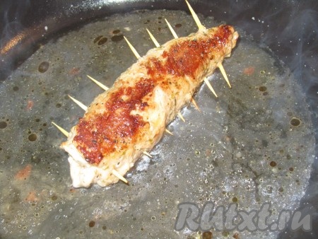 Обжариваем свиной рулет на растительном масле н огне чуть выше среднего с двух сторон до золотистого цвета, затем добавляем 0,5 стакана воды и протушиваем минут 15 на минимальном огне под крышкой (воду можно подливать). Когда мясо готово (я проверила ножиком, отрезав кусочек, - срез готового мяса должен быть белым, без вкраплений крови), снимаем крышку, достаём зубочистки и ещё раз поджариваем рулет до золотого цвета с двух сторон на среднем огне.
