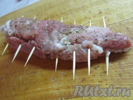 Начиная с широкого края, сворачиваем свинину в рулетик, скрепив его зубочистками.