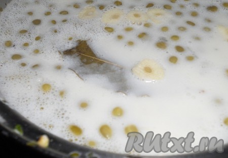 Затем добавить консервированный горошек и нарезанный на дольки чеснок, дать закипеть, снять с огня.
