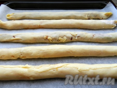 Свернуть каждую часть теста в рулет и выложить на противень, застеленный бумагой. Рулеты нужно выкладывать на расстоянии друг от друга, так как они увеличатся в процессе выпечки.
