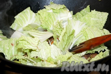 Пекинскую капусту нарезать небольшими кусочками, добавить в вок. Посолить, поперчить, перемешать и жарить 5 минут.
