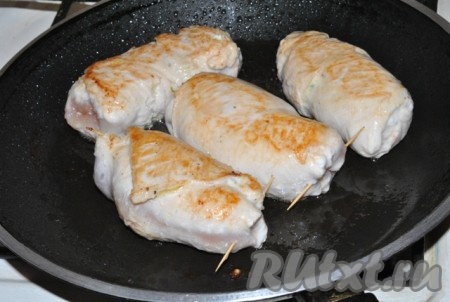 На сковороде разогреть растительное масло. Затем выложить 4 сформированных куриных рулетика с творожной начинкой, обжарить их на среднем огне с двух сторон до лёгкой золотистой корочки.