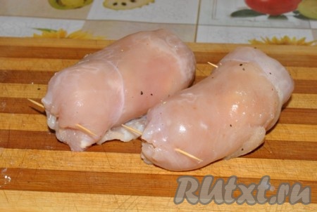 Начиная с более узкой стороны, свернуть каждое куриное филе с творогом и зеленью в рулетик. При необходимости можно зафиксировать края рулетиков зубочистками.