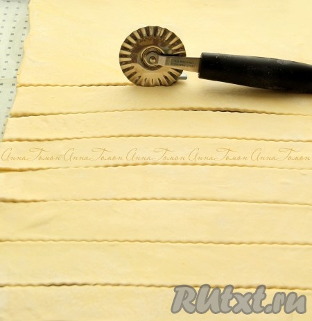 Слоёное тесто раскатать до толщины 3 миллиметра, нарезать полосками шириной 2 сантиметра.