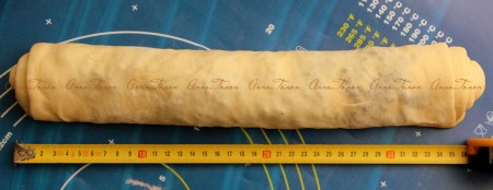 Посыпьте тесто шоколадной крошкой, равномерно распределите. Сверните тесто в тугой рулет, начиная с короткой стороны.