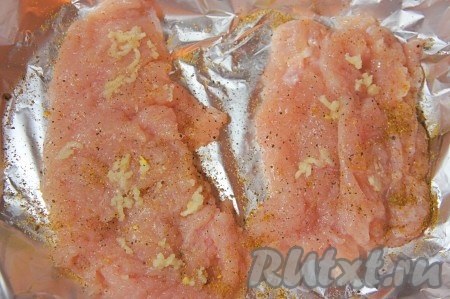 Куриное филе вымыть, обсушить нарезать на порционные кусочки (я разрезала 1 куриное филе вдоль на 2, примерно, равные части). Чеснок пропустить через пресс. Куриное филе отбить с одной стороны, натереть смесью соли, перца и чеснока. Форму для выпечки застелить фольгой, выложить на неё рядом 2 подготовленные куриные отбивные и оставить мясо "отдохнуть" на 5-10 минут.