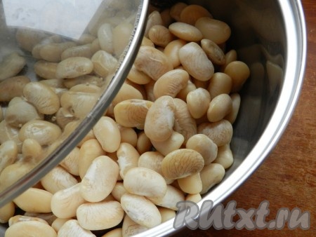 Для этого блюда я взяла крупную белую сухую фасоль сорта "Лима". Фасоль выложить в глубокую миску, полностью залить холодной водой и оставить на 6-7 часов (я оставила на ночь). Затем воду слить, выложить фасоль в кастрюлю, залить полностью чистой холодной водой и поставить на сильный огонь. После закипания воды уменьшить огонь и отварить фасоль до готовности (фасоль должна стать мягкой, но не разваренной). Длительность отваривания фасоли зависит от её сорта (в среднем на варку требуется от 45 минут до 1,5 часов). После того как фасоль станет достаточно мягкой, воду нужно слить.