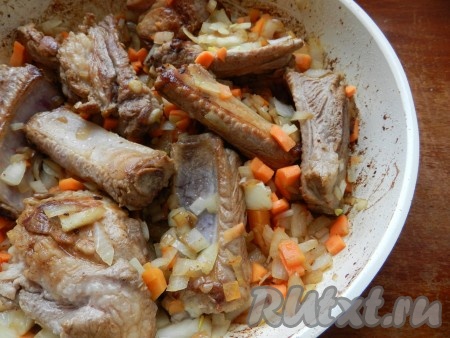 Обжаренные овощи переложить в сковороду со свиными рёбрышками, перемешать, влить воду, чтобы она доходила до половины мяса, дать воде закипеть. Накрыть сковороду крышкой и тушить мясо 20 минут на небольшом огне.