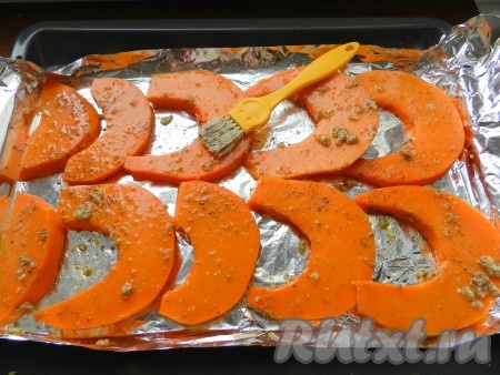 Противень для выпечки застелить фольгой, выложить ломтики тыквы и смазать их получившейся масляной смесью.