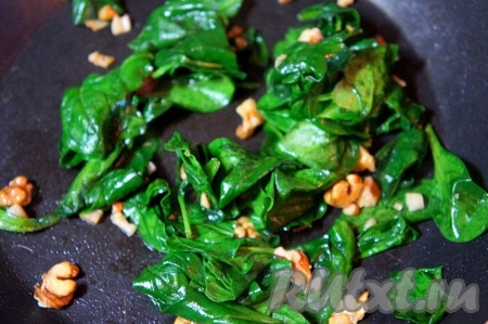 На сковороде нагреть 1 столовую ложку оливкового масла, добавить мелко нарезанный чеснок, слегка его обжарить, добавить грецкие орешки, шпинат, слегка посолить его. Готовить 1-2 минуты при постоянном помешивании. Шпинат должен значительно уменьшиться в размерах и стать немного мягким.
