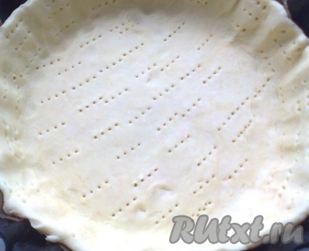 Прежде всего замесим песочное тесто. Для этого в посуду нальём холодную кипячёную воду и отправим в морозилку. Муку просеем, добавим соль, перемешаем. В муку с солью добавляем крупно нарезанное охлаждённое масло (или натёртое на тёрке замороженное масло), рубим ножом до образования крупной крошки. Достаём воду из морозилки и вливаем по одной столовой ложке за раз, после каждого раза перемешивая тесто. Затем собираем тесто в ком руками, заворачиваем в плёнку и отправляем в холодильник на полчаса. Форму диаметром 23-25 сантиметров застилаем пергаментом. Достаём тесто из холодильника, раскатываем песочное тесто до толщины 2-3 миллиметра, выкладываем в форму. Тесто придавливаем, чтобы нигде не осталось воздушных карманов. Бортики не делайте высокими, они могут опадать. Накалываем тесто вилкой по всей площади. Можно сверху насыпать какой-нибудь груз, например, фасоль, чтобы песочное тесто во время выпечки сохранило форму. Выпекаем в разогретой духовке при температуре 200 градусов 20-25 минут (до готовности).