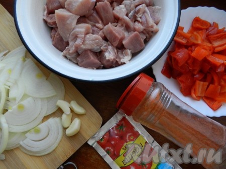 Подготовить продукты для приготовления пёркёльта из свинины. Свинину нарезать на небольшие кусочки. Лук очистить и нарезать полукольцами. Болгарский перец очистить от семян и нарезать квадратиками. Зубчики чеснока пропустить через пресс.