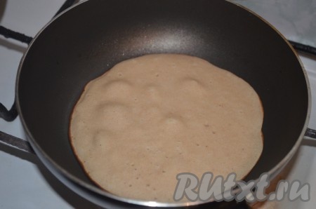 Разогреть сковороду, смазать её растительным маслом, выложить часть блинного теста, равномерно распределить. Жарить гречневый блин с двух сторон до румяности на среднем огне, затем переложить на тарелку. 