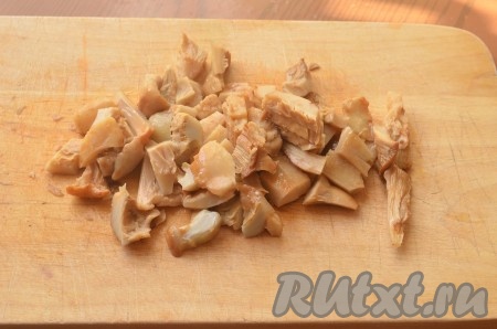 Соленые грибы нарезать небольшими кусочками. Добавить грибы, лук и чеснок в салатницу.
