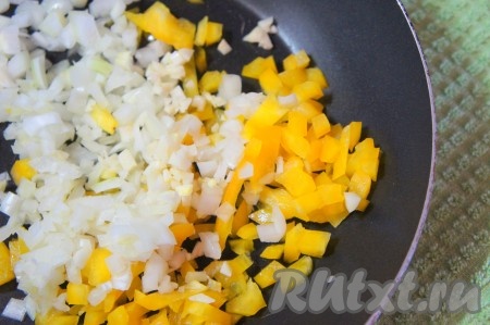 Тем временем приготовим начинку для куриных рулетиков. Болгарский перец промыть, убрать плодоножку, перегородки и семена. Нарезать перец на мелкие кубики, добавить очищенный и мелко нарезанный лук, 1 зубчик пропущенного через пресс чеснока, посолить, положить специи по вкусу и обжарить на среднем огне с добавлением небольшого количества оливкового масла до прозрачности лука (на это потребуется около 4-5 минут). В процессе обжаривания не забывайте помешивать овощи, чтобы они не подгорели. Снять начинку с огня и дать остыть.