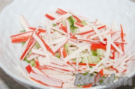 Крабовые палочки, заранее размороженные при комнатной температуре и очищенные от слюды, нарезать тонкими палочками и добавить к огурцам.