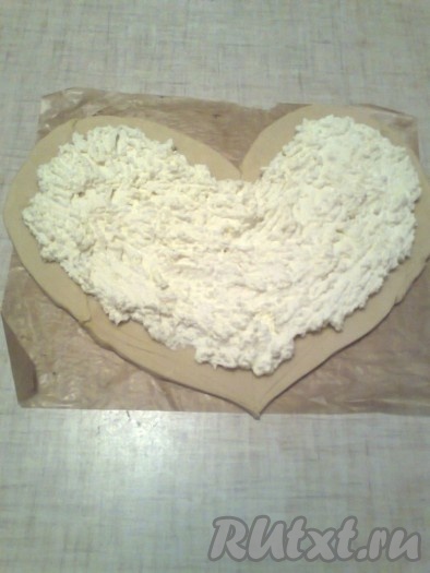 Яблоки нарезать ломтиками. Тесто раскатать в прямоугольник толщиной 0,5 см. Вырезать сердечко, из остатков теста вырезать маленькие сердечки. На выстланный пергаментом противень выложить тесто. На тесто поместить начинку из творога.