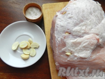 Свинину вымыть, обсушить бумажными полотенцами. Очистить чеснок, если зубчики крупные, разрезать их на части. В мясе сделать небольшие надрезы острым ножом. Дольки чеснока окунуть в соль и вставить в надрезы.