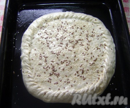 Накрыла другим пластом и защипнула края. Смазала верх пирога маслом, посыпала льняными семенами и кунжутом.
