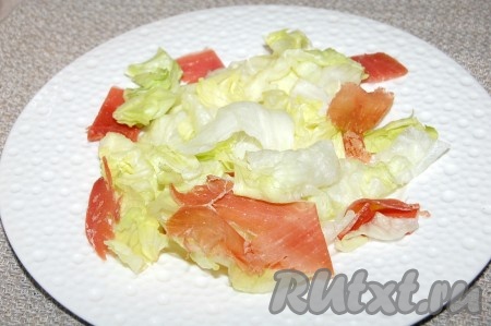 Ветчину нарезать некрупными кусками и разложить на салате.
