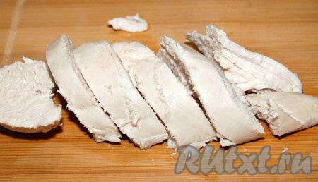 Куриную грудку положить в кипящую воду, довести до кипения и варить 25 минут. Выключить огонь и вытащить грудку из бульона. Остудить и нарезать поперек волокон.