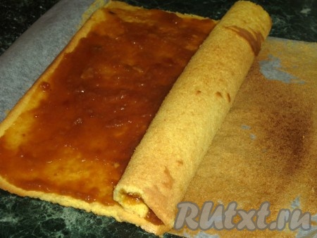 Свернуть бисквит рулетом с помощью бумаги.
