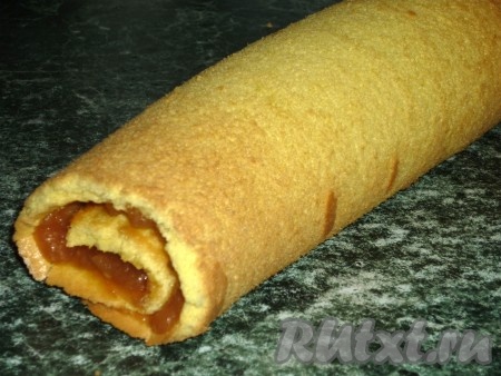 Свернуть бисквит рулетом с помощью бумаги.