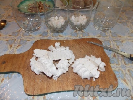 Грецкие орехи измельчить. Зефир порезать кубиками. Половину зефира выложить на дно бокала или креманки. Это будет первый слой нашего десерта.
