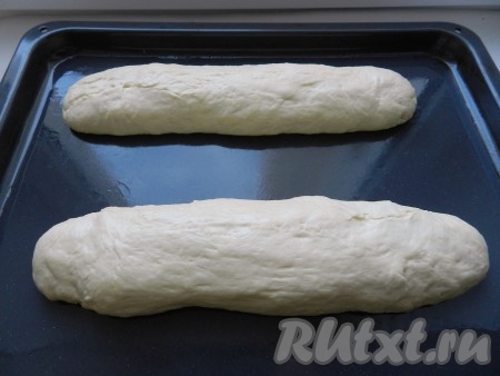 Духовку разогреть до 220 градусов. Разделить тесто на 2 части. Противень смазать маслом. Из теста сформовать два французских багета, выложить на противень и дать подойти 10 минут.
